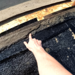 A forensic roof inspector pointing to a deteriorated bitumen substrate layer, assessing a property for Storm Damage Roof Repair in Cincinnati, OH, with Eckstein Roofing.