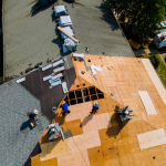 An aerial perspective of a residential roof replacement project with active teardown and plywood deck staging, exploring options for Metal vs Asphalt Roofing with Eckstein Roofing Co.